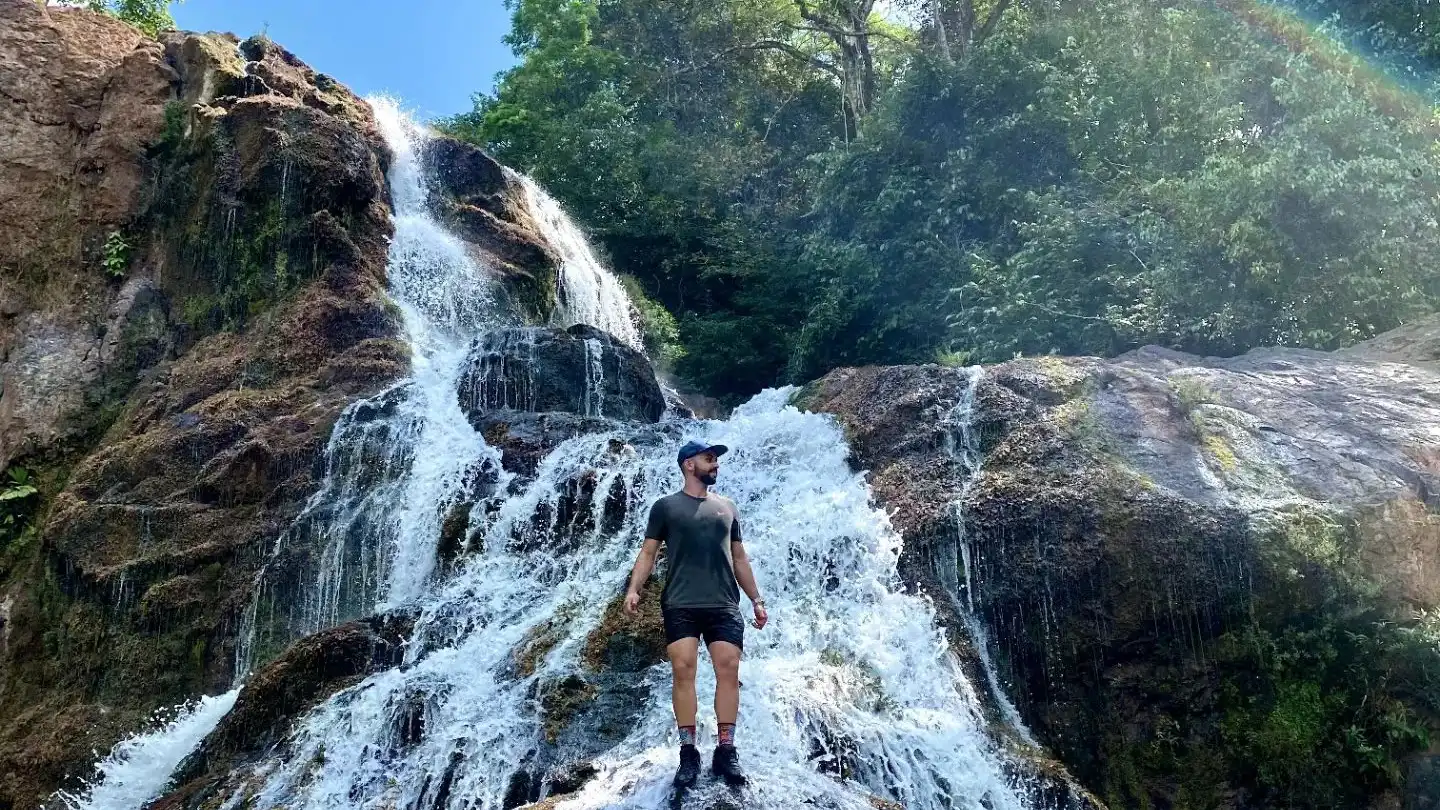 Un homme debout devant une cascade