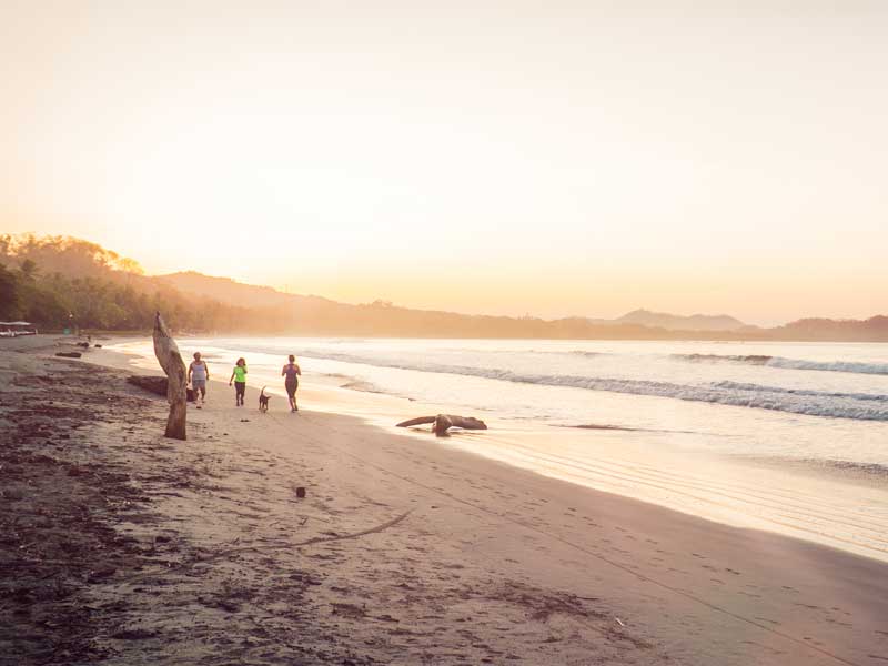 Un groupe de personnes se tenant au sommet d'une plage de sable.