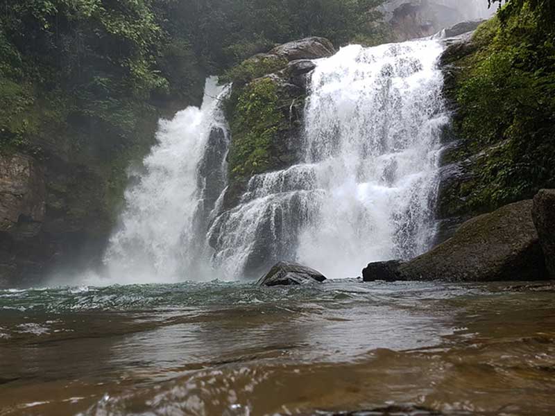 Un homme debout dans une rivière à côté d'une cascade.