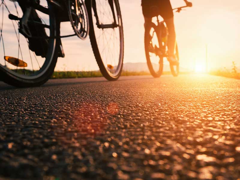 Une personne circulant à vélo dans une rue au coucher du soleil.