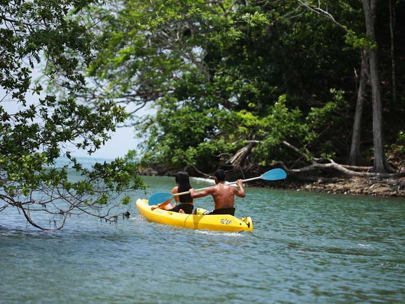 Un homme pagaie sur un kayak dans l'eau.