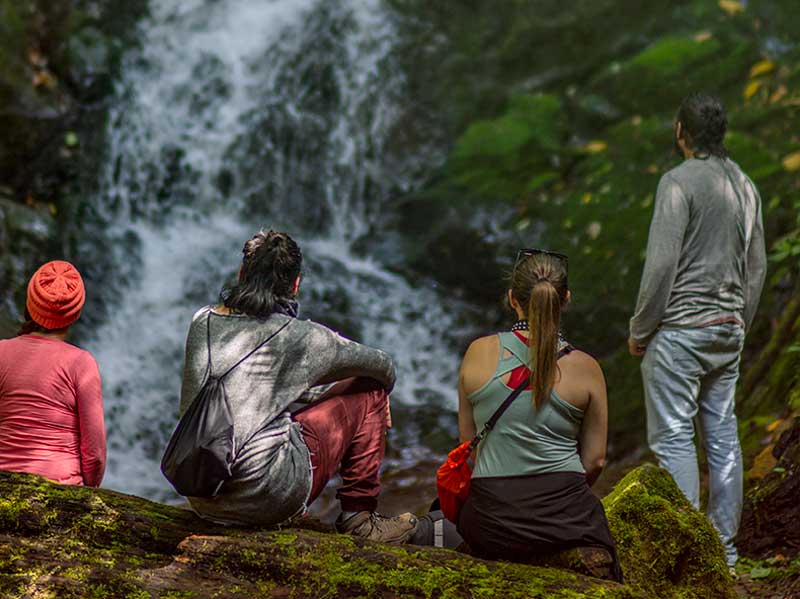 Un groupe de personnes assises sur un rocher regardant une chute d'eau.