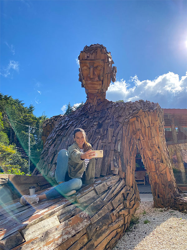 Une femme assise sur une sculpture en bois.