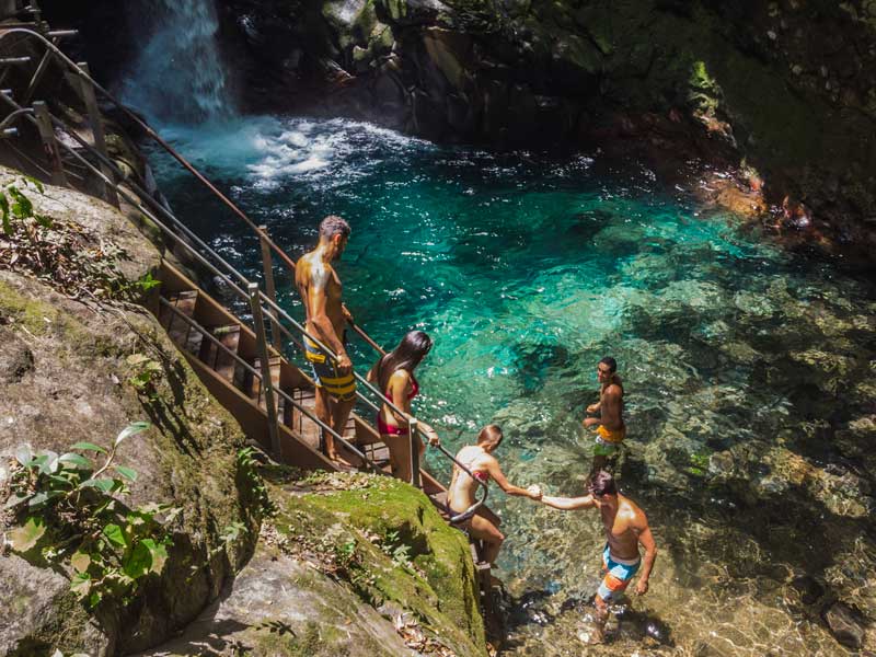 Un groupe de personnes se tenant au sommet d'une falaise près d'une chute d'eau.
