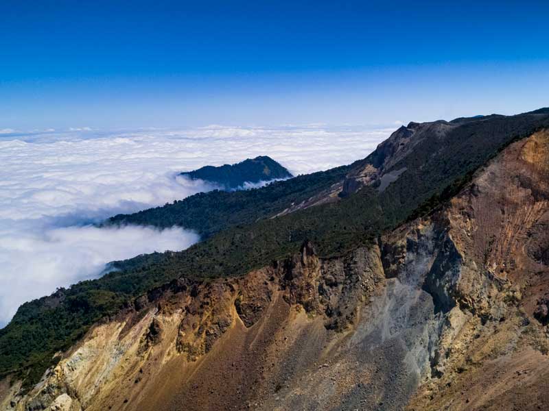 Vue du sommet d'une montagne avec des nuages en contrebas.