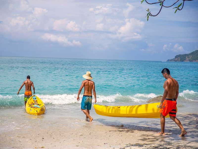Un groupe de personnes sur une plage avec une planche de surf jaune.