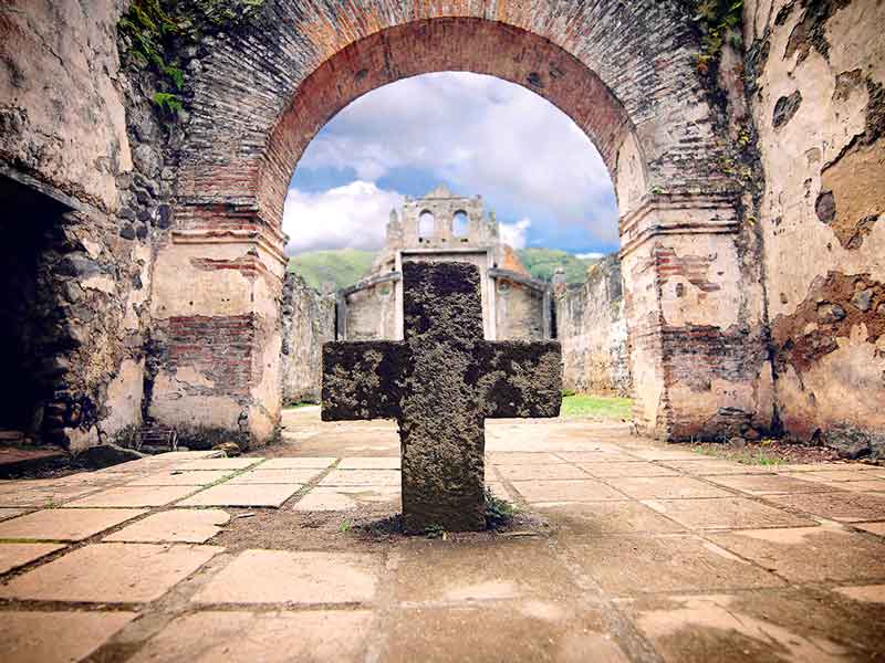 Une croix de pierre au milieu d'une cour.