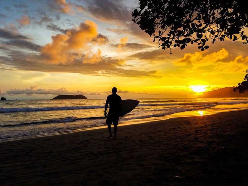 Un homme tenant une planche de surf sur une plage.