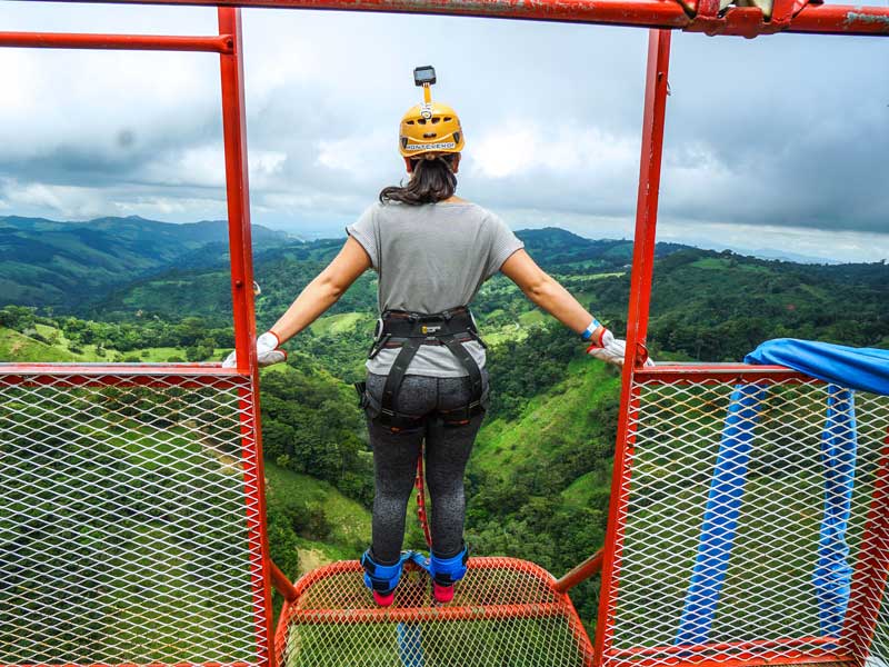 Une femme debout au sommet d'une haute structure métallique.