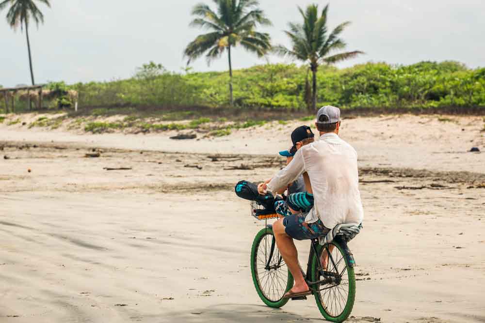 Un homme et un garçon à vélo sur une plage.