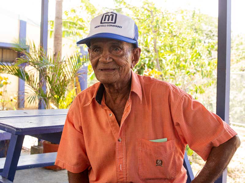 Un vieil homme portant un chapeau, assis à une table de pique-nique.