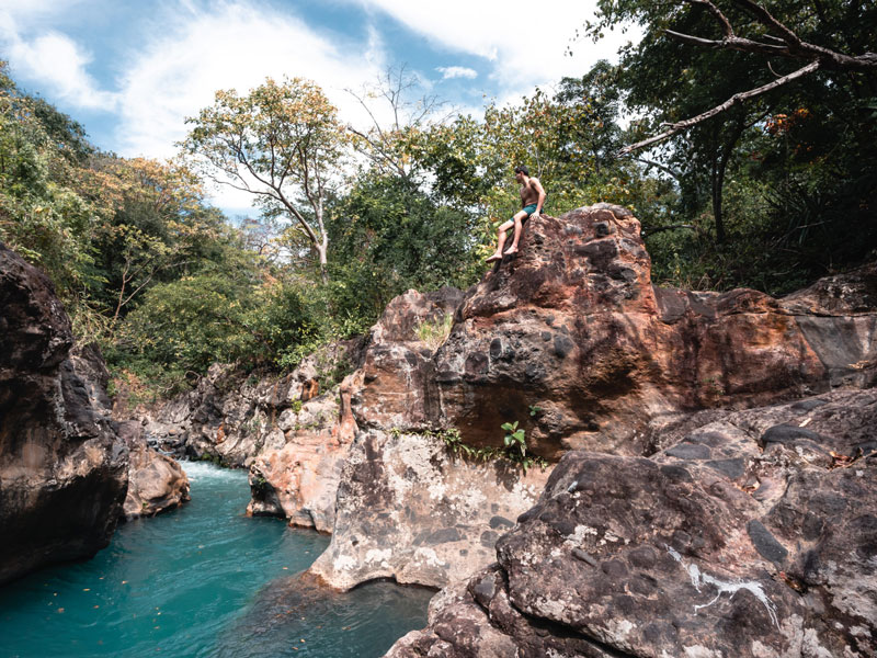 Une personne assise sur un rocher au-dessus d'une rivière.