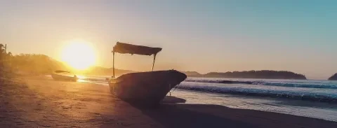 La vue du soleil couchant et de l'océan, avec le bateau échoué sur la plage