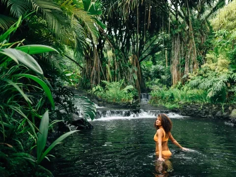 une femme marchant près d'une source dans la jungle