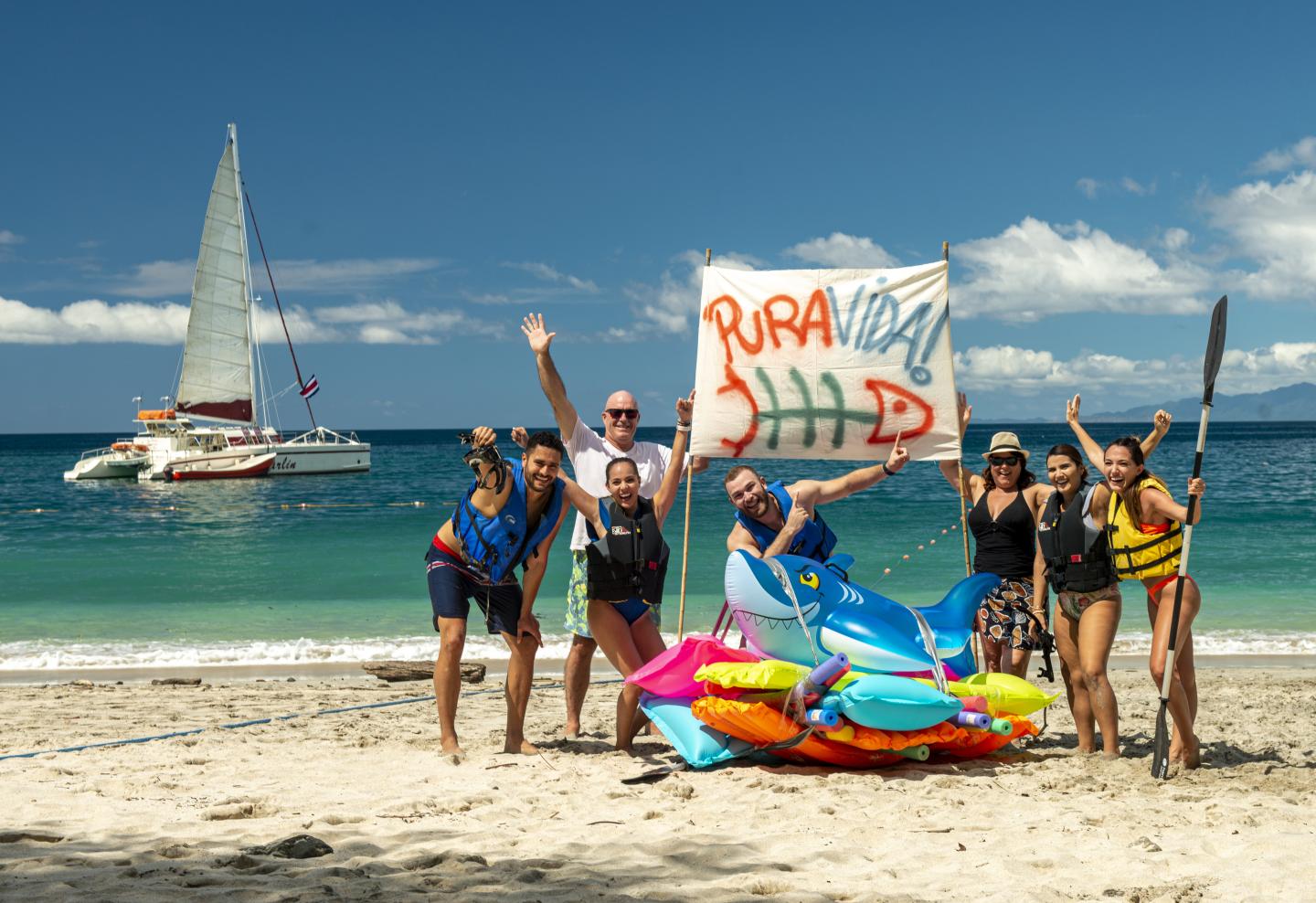 Personnes sur la plage avec un panneau " pura vida ".