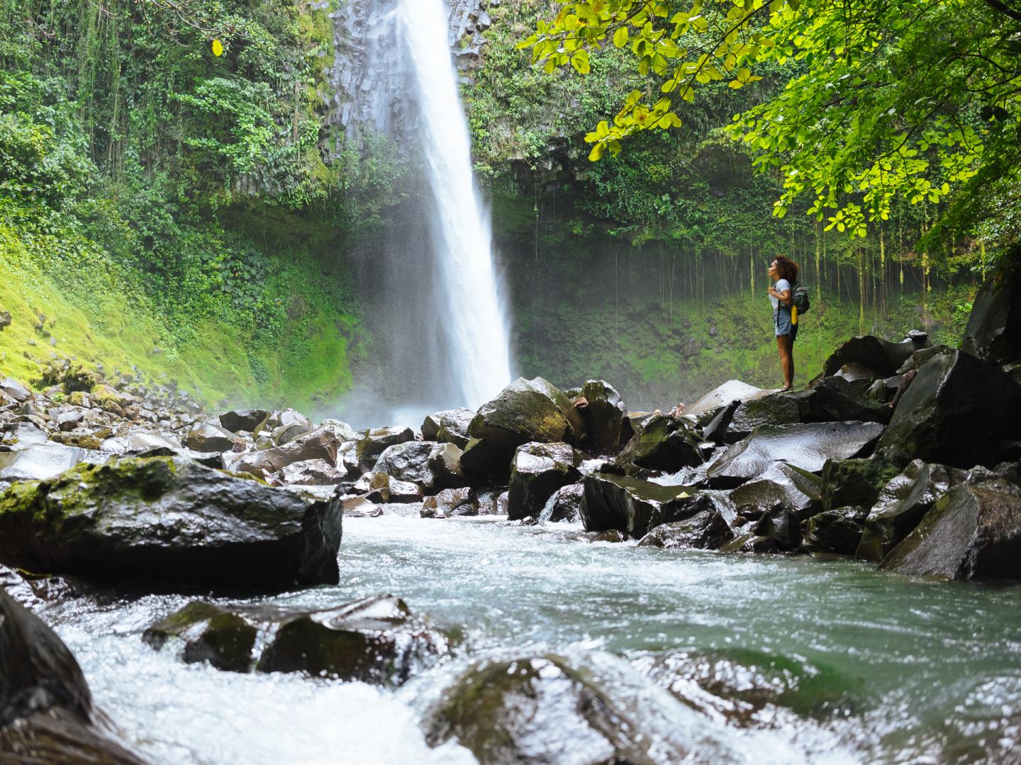 Femme debout près d'une cascade dans la jungle