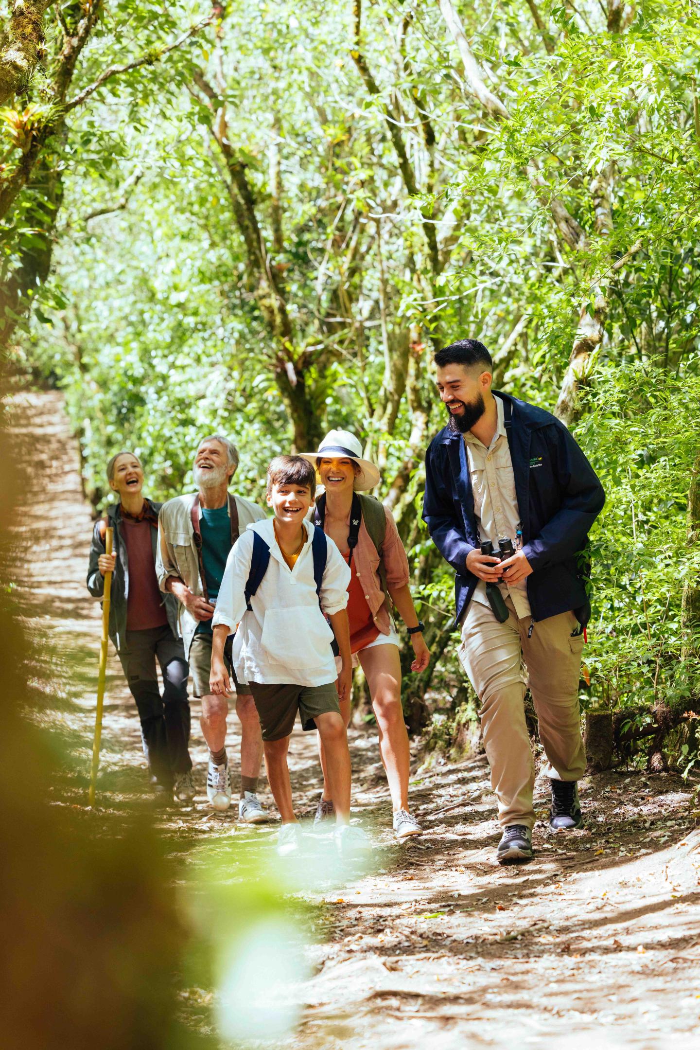 Un petit groupe de voyageurs se promène sur un sentier forestier ombragé en compagnie d'un guide.
